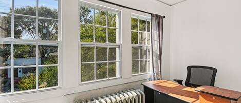 A room with a large window, a radiator, and a desk with a chair.