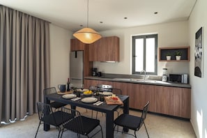 Une cuisine moderne avec des meubles en bois, une table à manger avec des chaises et un four à micro-ondes encastré.