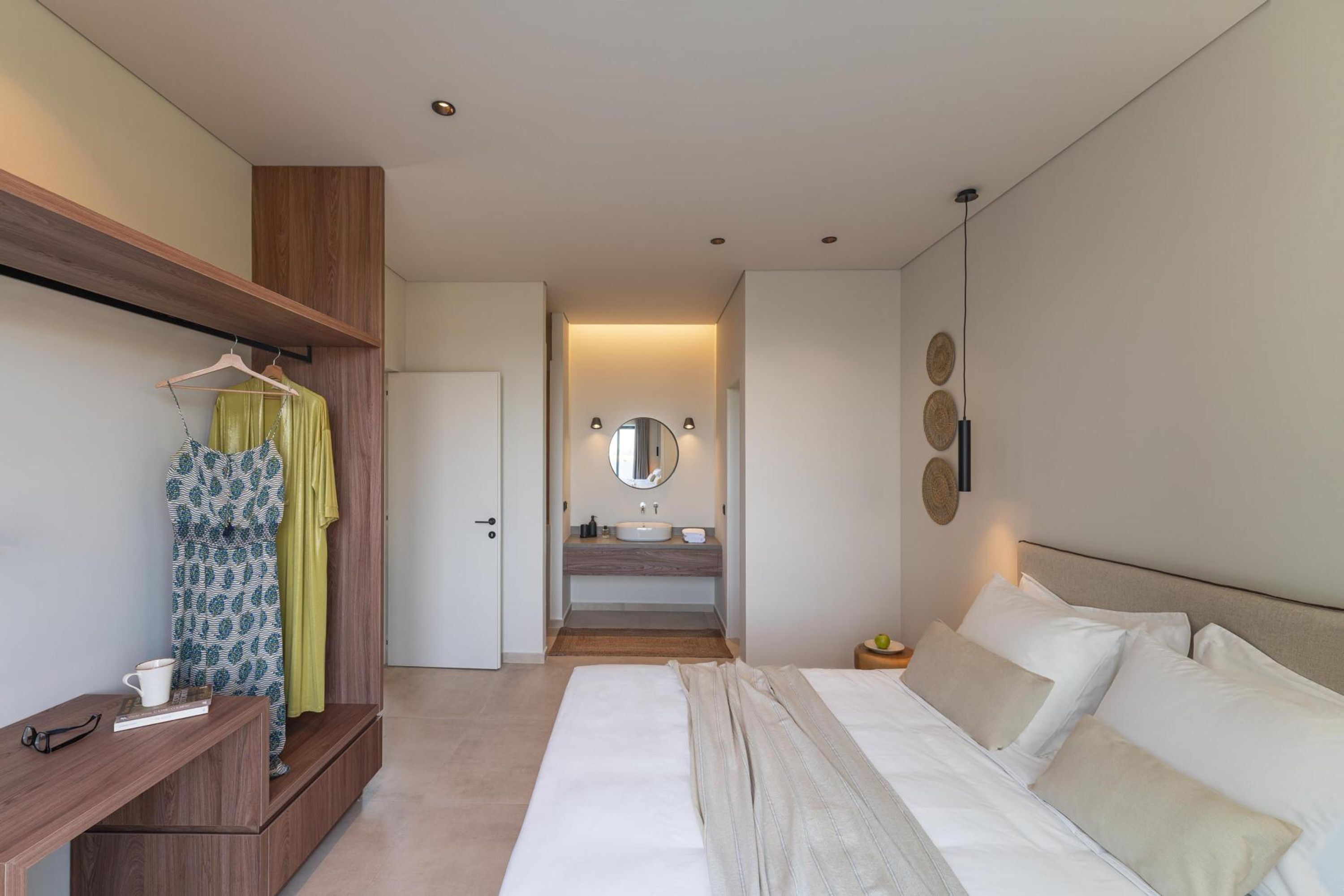 Une chambre d’hôtel moderne dotée d’un grand lit, d’une armoire en bois, d’un miroir et d’une salle de bain avec un lavabo et un miroir.