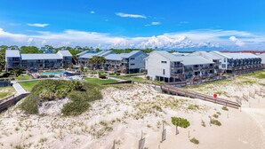 A beachfront hotel with multiple-story buildings, a swimming pool, and a boardwalk leading to the beach. - 1-minute walk to beach, Townhome in Welcoming Old Florida Saint George Island! (Saint George Island)