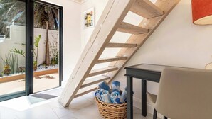 A modern interior with a wooden staircase, a wicker basket with towels, and a view of the outdoors. - Stunning Views, Walk to Beach, Heated Splash Pool - Iparadesi (Cape Town)