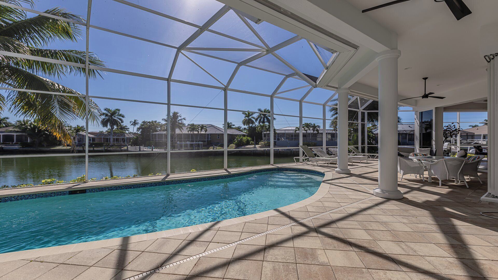 A pool area with a clear view of the surrounding landscape, including palm trees and houses.