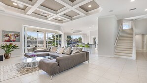 A spacious living area with a sectional sofa, a coffee table, and a view of the backyard through large sliding glass doors. - Tranquil Island Retreat with Modern Comforts (Marco Island)