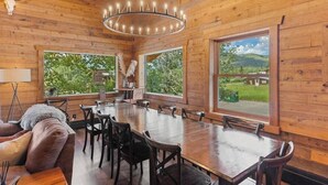 Ein Holzkaminzimmer mit großem Esstisch, Stühlen und einer Chandelier.