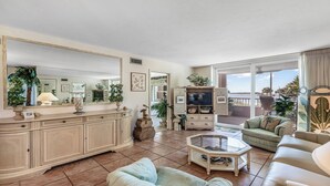Un salon spacieux avec un grand miroir, une télévision et un balcon offrant une vue agréable.