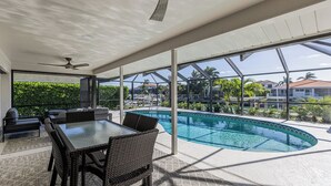 Een modern buitenzwembad met een glazen patio, een pooltafel en comfortabele zitplaatsen.
