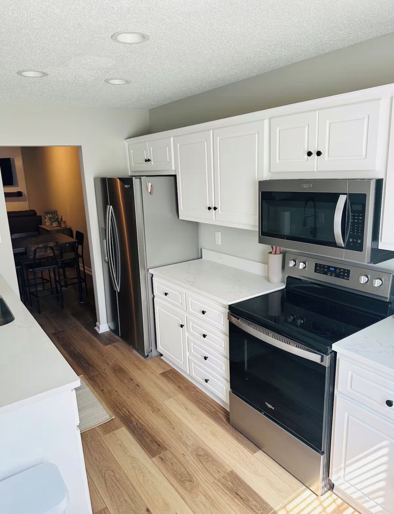 Una cocina moderna con armarios blancos, electrodomésticos de acero inoxidable y suelo de madera.