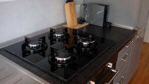 A kitchen with four black gas burners, a wooden knife block, and a black countertop. - Trastevere Terrace Bright Apartment (Roma)