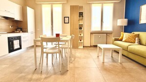 Uma sala moderna com área de jantar, sofá e cozinha ao fundo.