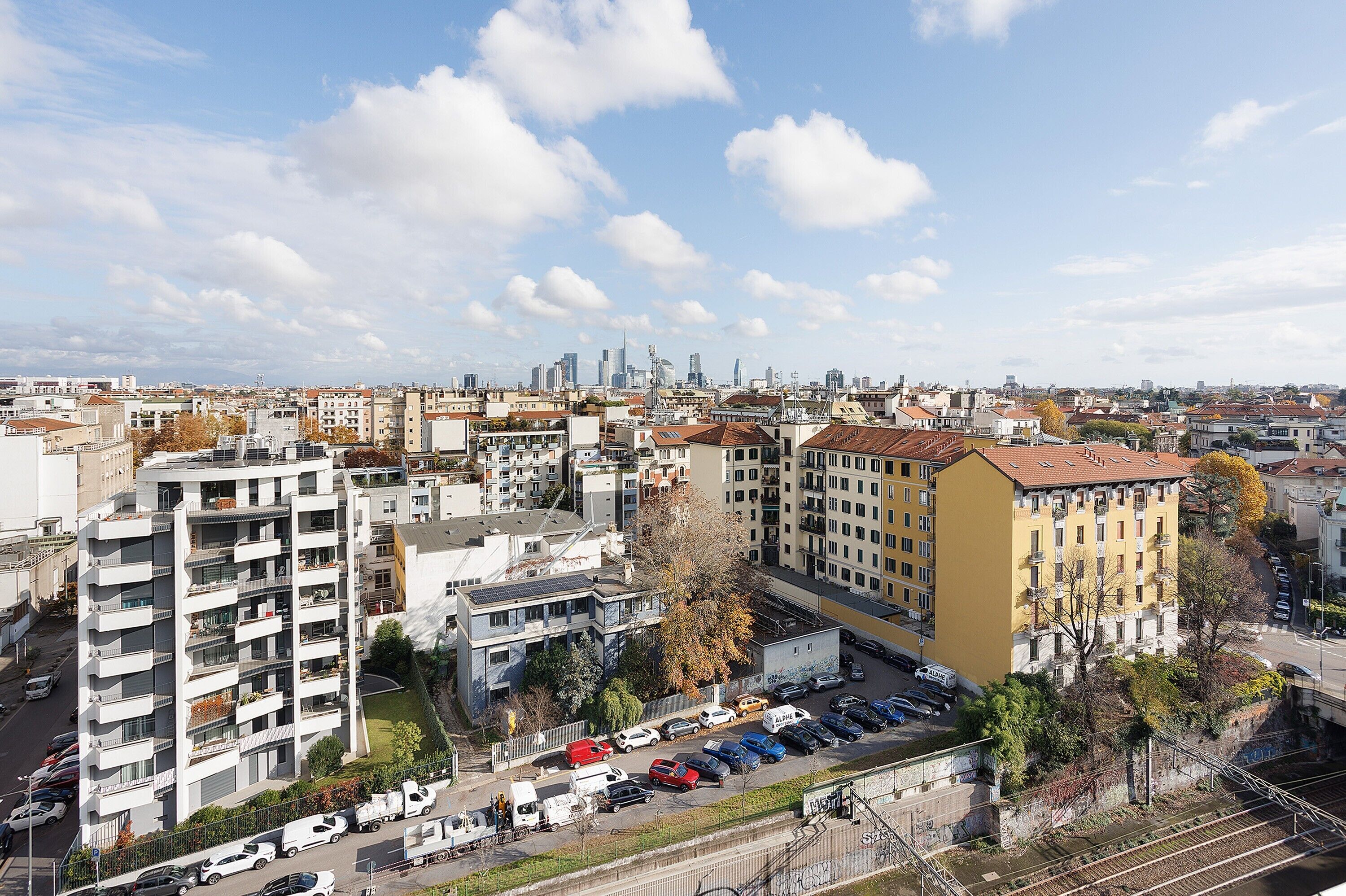 Un paysage urbain mêlant bâtiments modernes et traditionnels, une zone de stationnement et un ciel dégagé.
