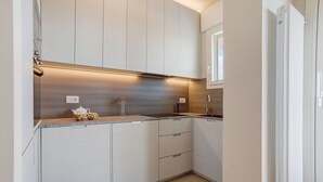 Eine moderne Küche mit hellen Schränken, einer Edelstahl Arbeitsplatte und einem eingebauten Backofen.