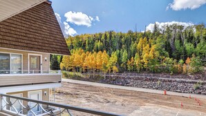 A hotel with a balcony overlooking a parking area and a forested hillside. - Family Ski Loft at Kristi – Walk to Chair 8, Game Room, Views (Brian Head)