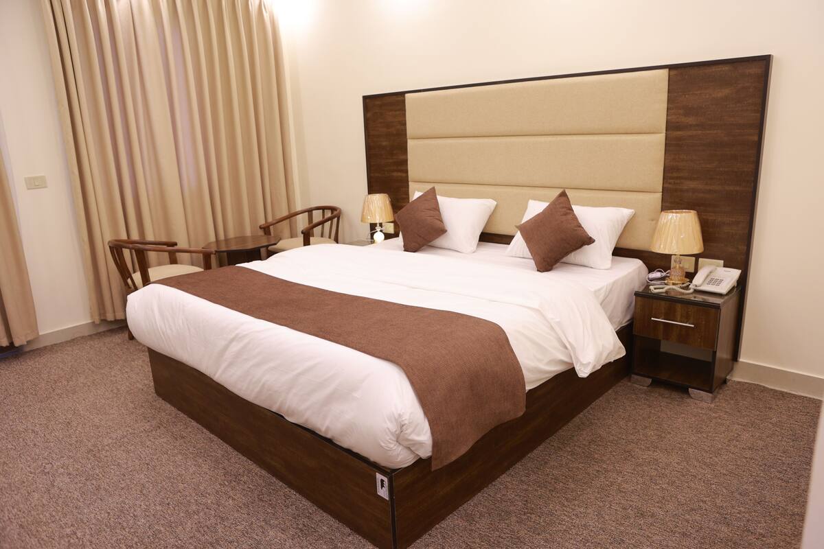 A hotel room with a large bed, bedside tables, a desk, and a chair.