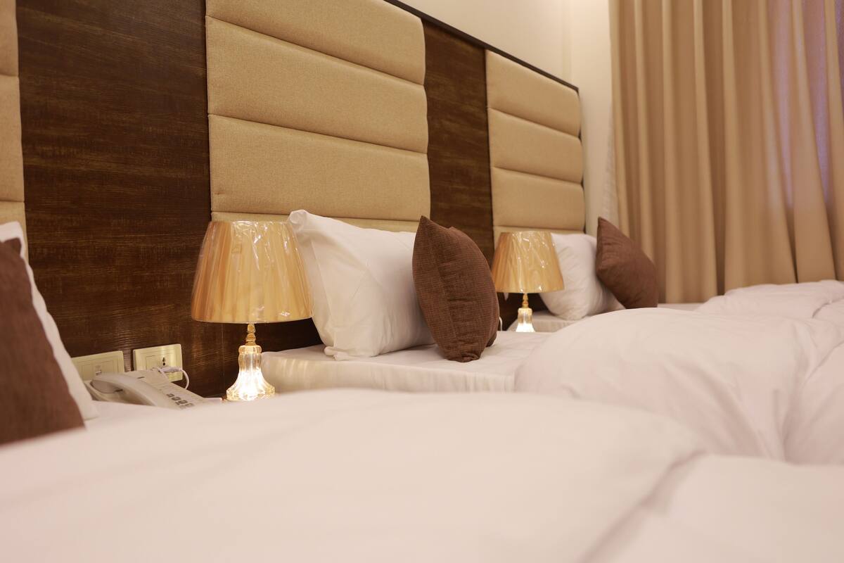 A hotel room with a large bed, two bedside lamps, a telephone, and a wooden headboard.