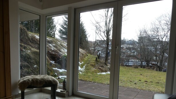 Une pièce dotée d’une grande porte-fenêtre coulissante qui donne sur un jardin avec une pelouse et des arbres.