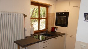 Une cuisine compacte dotée d’un four encastré, d’une fenêtre donnant sur un espace verdoyant et d’un radiateur.