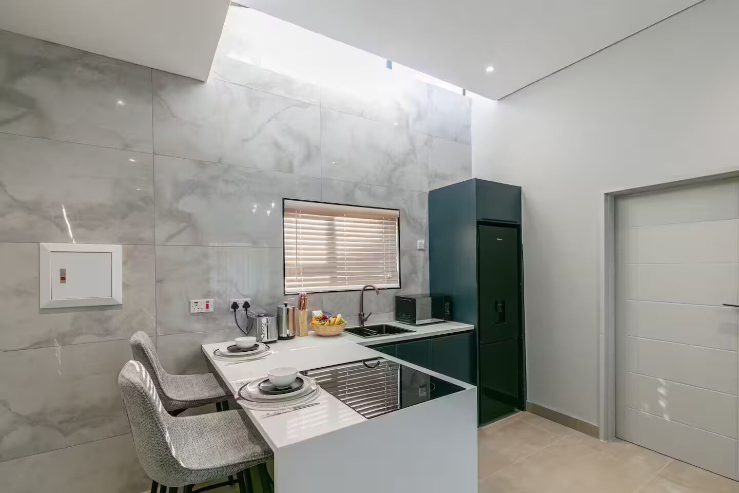 Eine moderne Küche mit Marmor-Spritzschutz, einer integrierten Kochinsel und einem dunklen Kühlschrank.