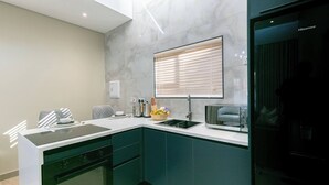 Una cocina moderna con armarios verde oscuro, una encimera negra y un horno empotrado.