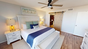 A bedroom with a bed, nightstands, a ceiling fan, a wooden wardrobe, and a sliding door.