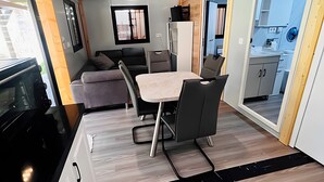A compact RV interior with a kitchenette, dining area, and a small seating space. - Tiny House 200 with Private Terrace, Garden, and Wi-Fi (Zadelsdorf)