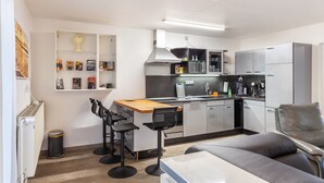 A compact kitchen with a dining area, bar stools, a sofa, and a radiator. - Holiday Apartment "Zum Segel" 2 with Private Terrace and Wi-Fi (Zadelsdorf)
