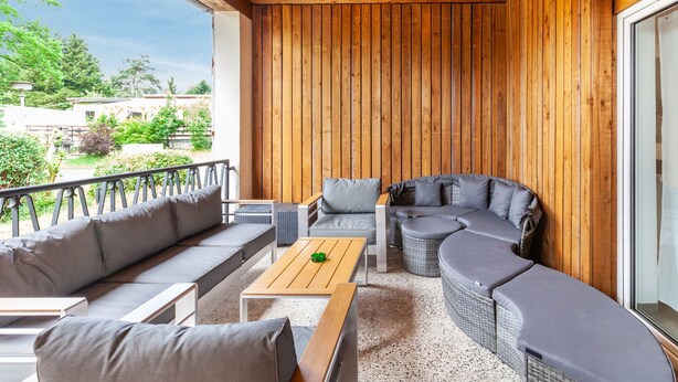A covered outdoor seating area with wooden walls, a sofa, a table, and a wicker sectional sofa. - Holiday Apartment "Zum Segel" 2 with Private Terrace and Wi-Fi (Zadelsdorf)
