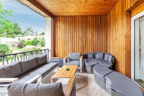 A covered outdoor seating area with wooden walls, a sofa, a table, and a wicker sectional sofa. - Holiday Apartment "Zum Segel" 2 with Private Terrace and Wi-Fi (Zadelsdorf)
