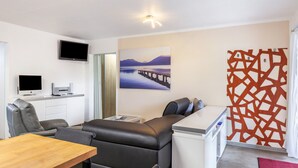 A modern room with a desk, computer, TV, seating area, and a painting. - Holiday Apartment "Zum Segel" 2 with Private Terrace and Wi-Fi (Zadelsdorf)