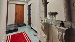 A hallway with a red carpet, a wooden door, a glass display case with decorative items, and an ornate wall arch. - The Pyramid Vault View INN (Giza)