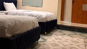 A hotel room with two beds, a large mirror, a wooden door, and a patterned rug. - The Pyramid Vault View INN (Giza)