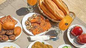 A table set with various breakfast items including bread, pastries, fruits, and beverages. - The Pyramid Vault View INN (Giza)