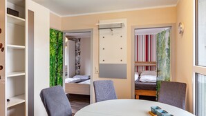Een moderne kamer met een ronde tafel, twee stoelen, een bed, een kledingkast en een klein raam.