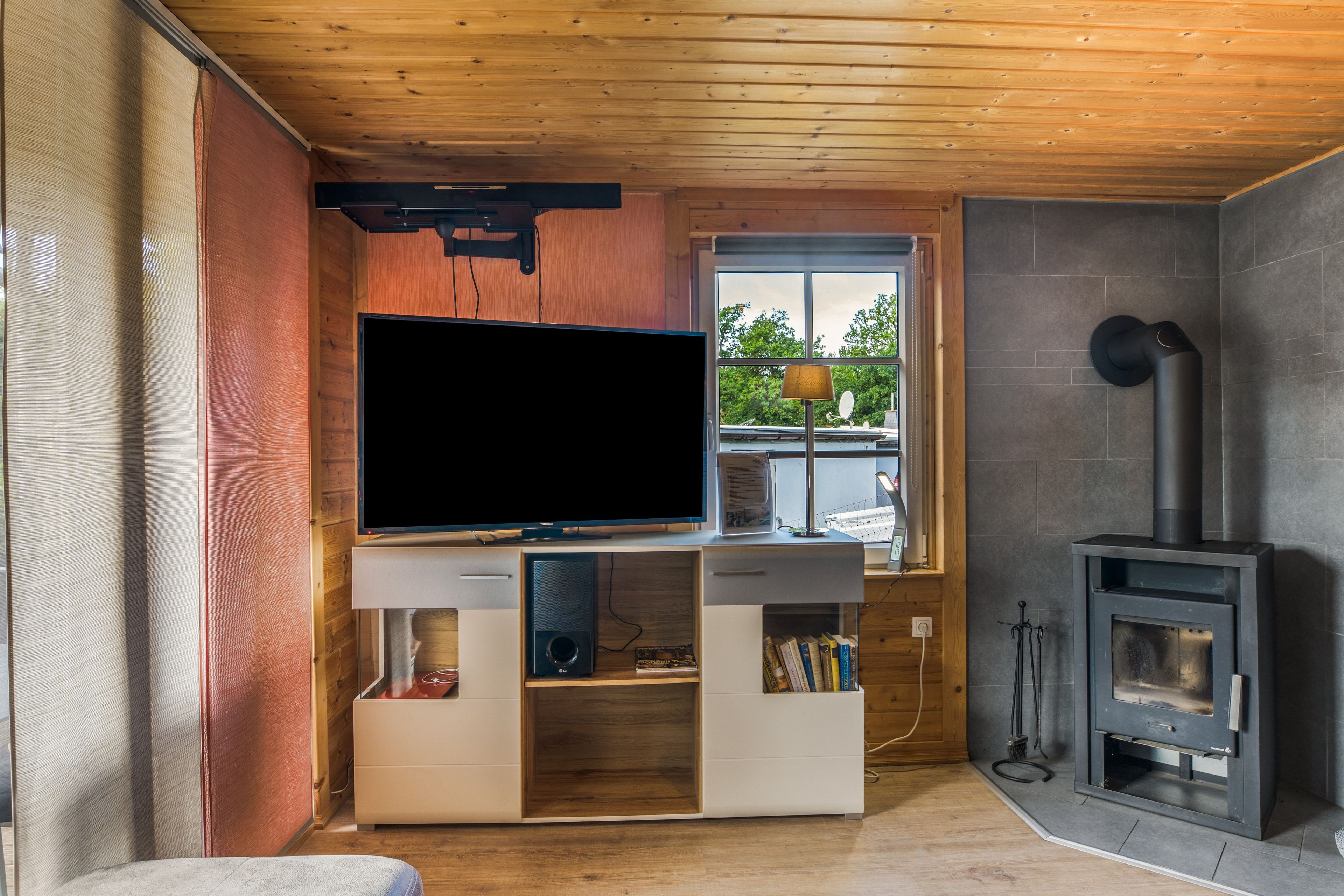 Ein modernes Wohnzimmer mit Flachbildfernseher, eingebautem Unterhaltungssystem und Kaminofen.