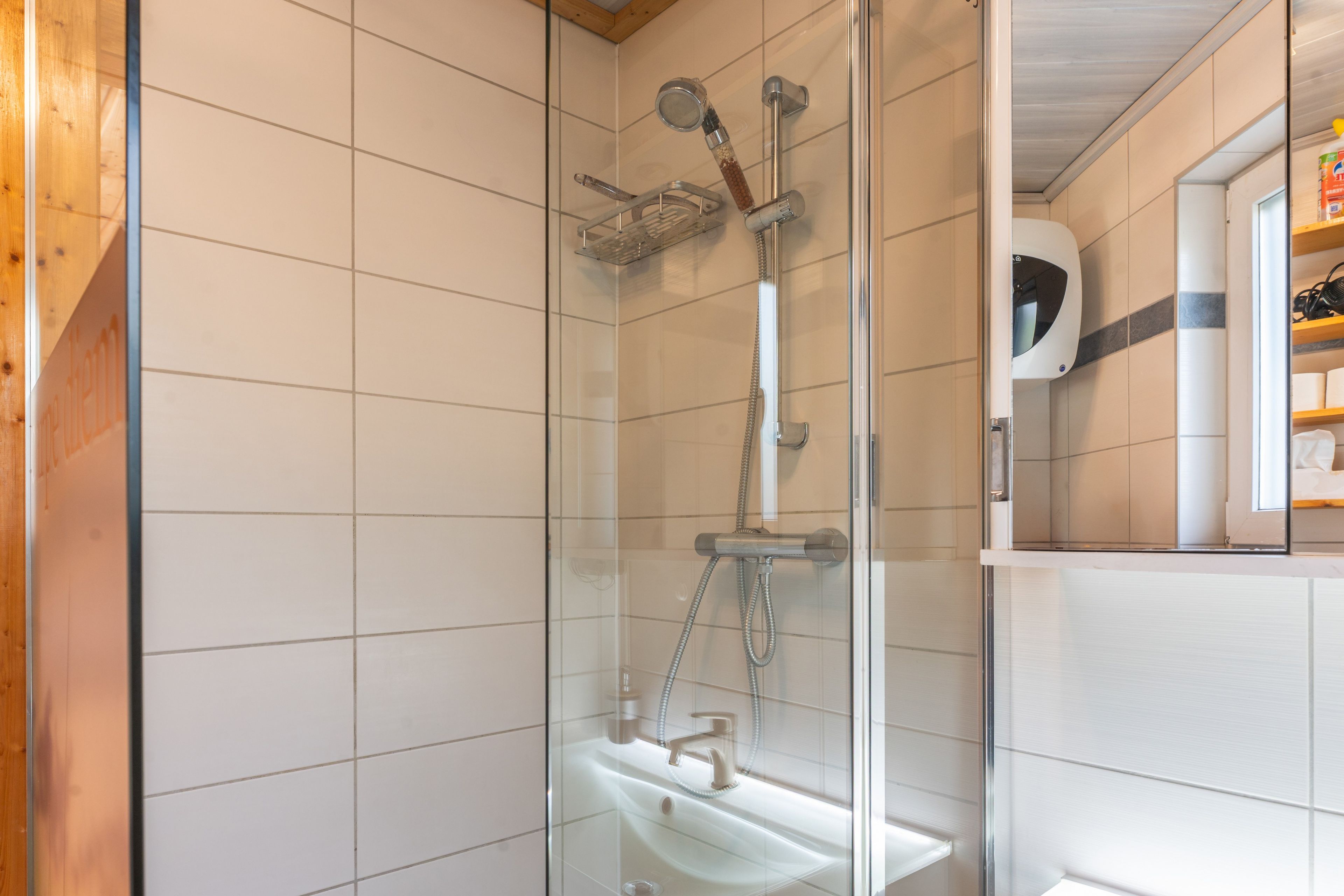 Eine moderne Dusche mit Glasabtrennung, einer Handbrause und einem wandmontierten Wasserhahn.