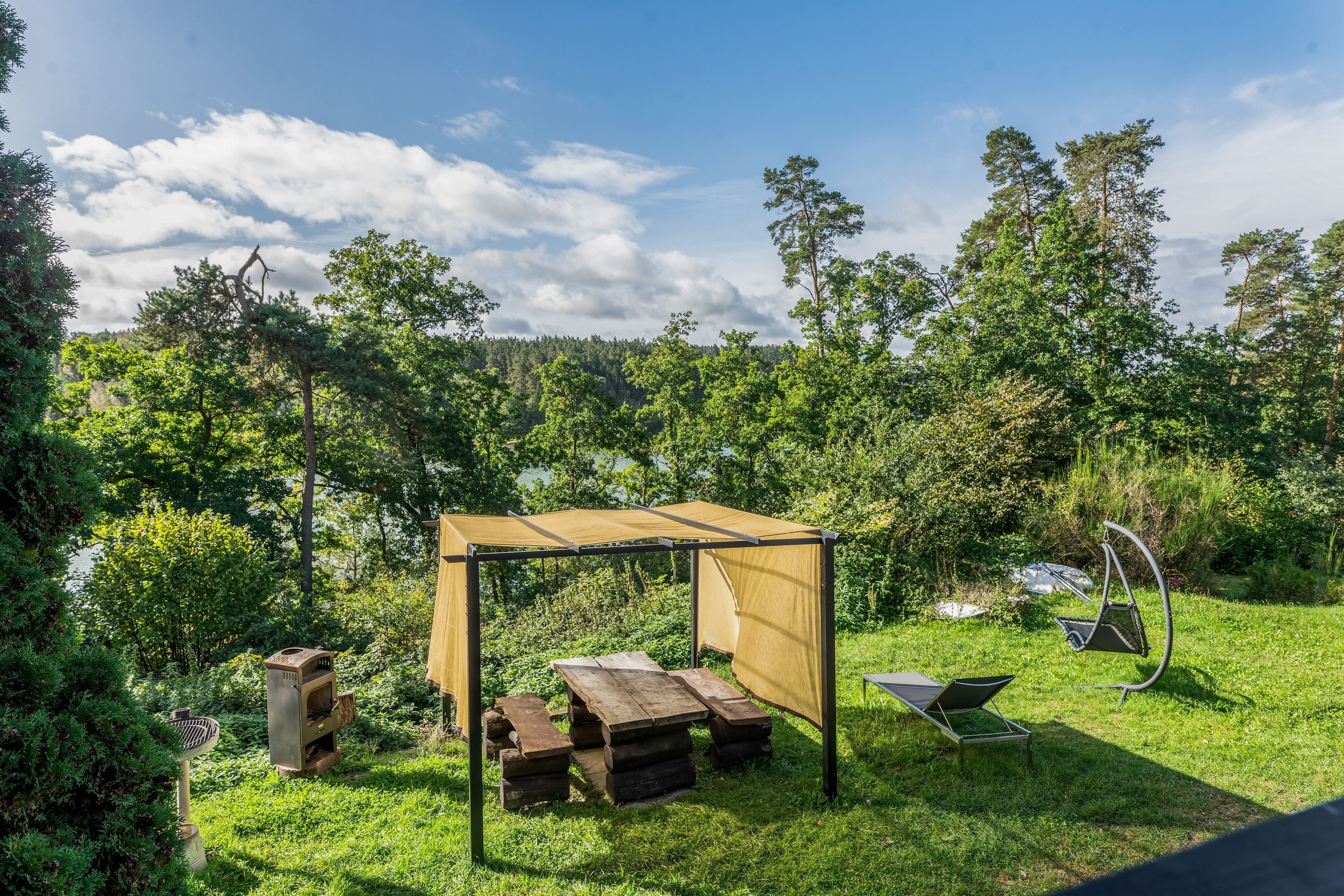 A garden with a wooden pergola, picnic table, and a swing set.