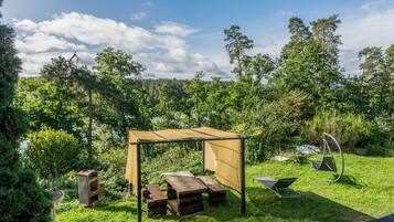 A garden with a wooden pergola, picnic table, and a swing set.