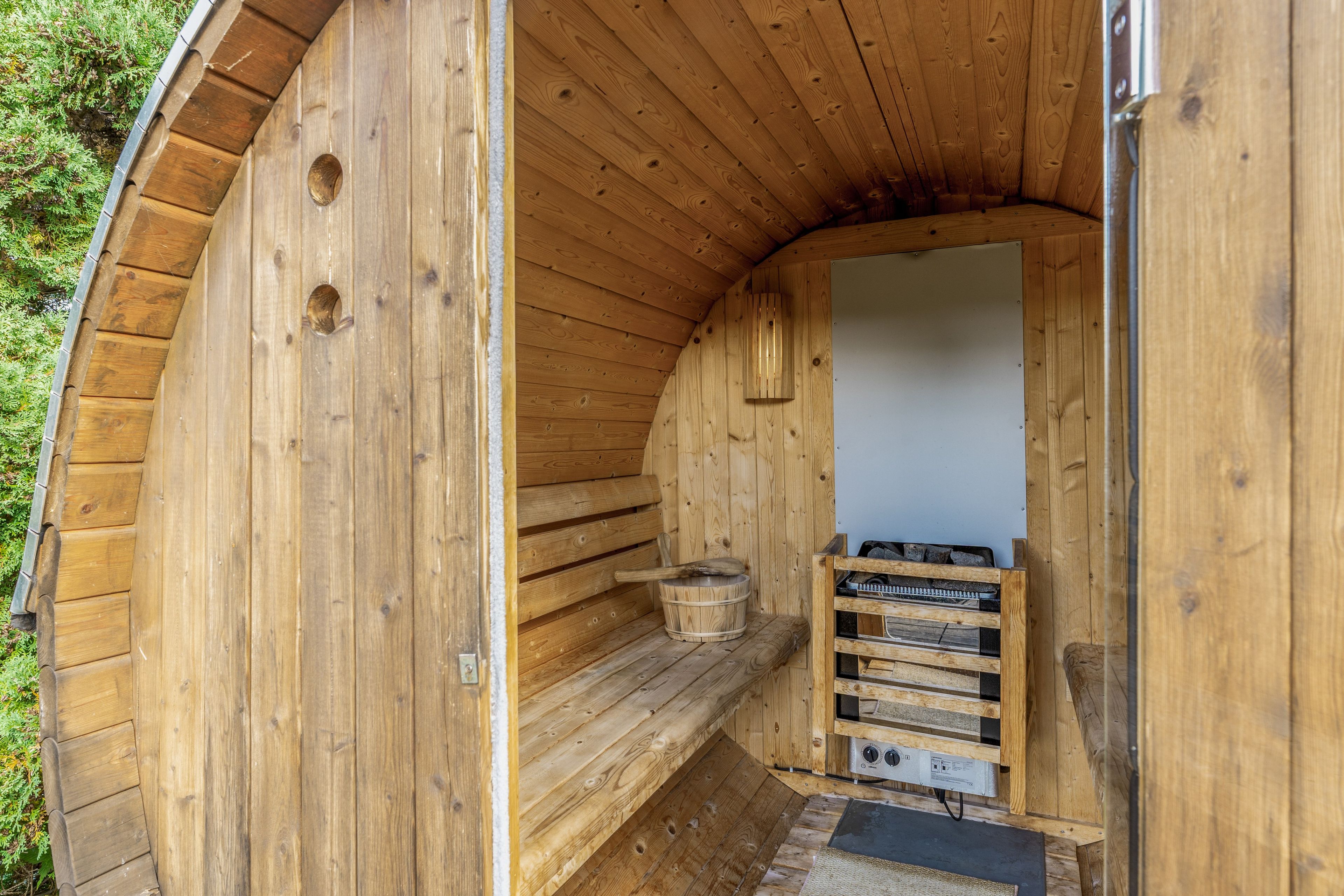 Eine Holzsauna mit einer Sitzbank, einem Eimer und einem Saunaofen.