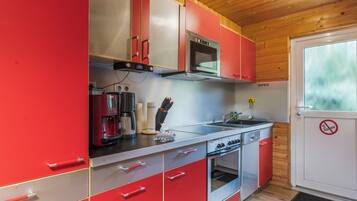 A kitchen with red cabinets, a Bosch oven, a coffee maker, and a microwave.