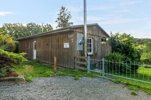 Ein Holzhaus mit einem Metallzaun, einem Schild mit der Aufschrift 'Ferienhaus 249' und einer Schotterauffahrt.