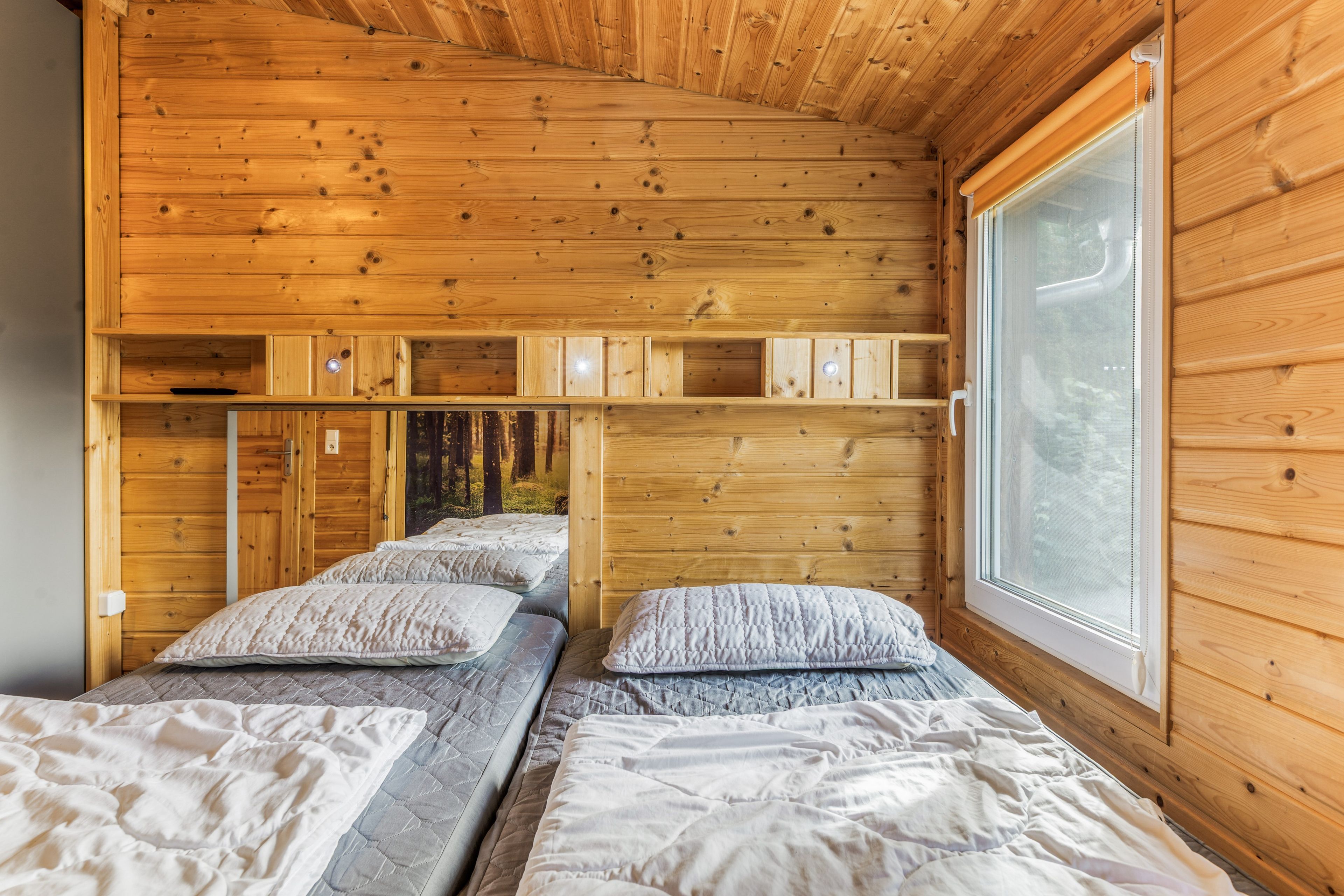 Uma cabana com duas camas, uma janela e paredes de madeira.