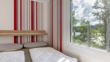 A room with a bunk bed, a window with a view of trees, and striped curtains.