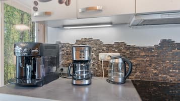 Een keuken met een koffiezetapparaat, een koffiekan en een waterkoker op het aanrecht.
