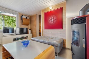 A modern kitchen with a built-in stove, a dining table with a blue bowl, and a red decorative wall panel.