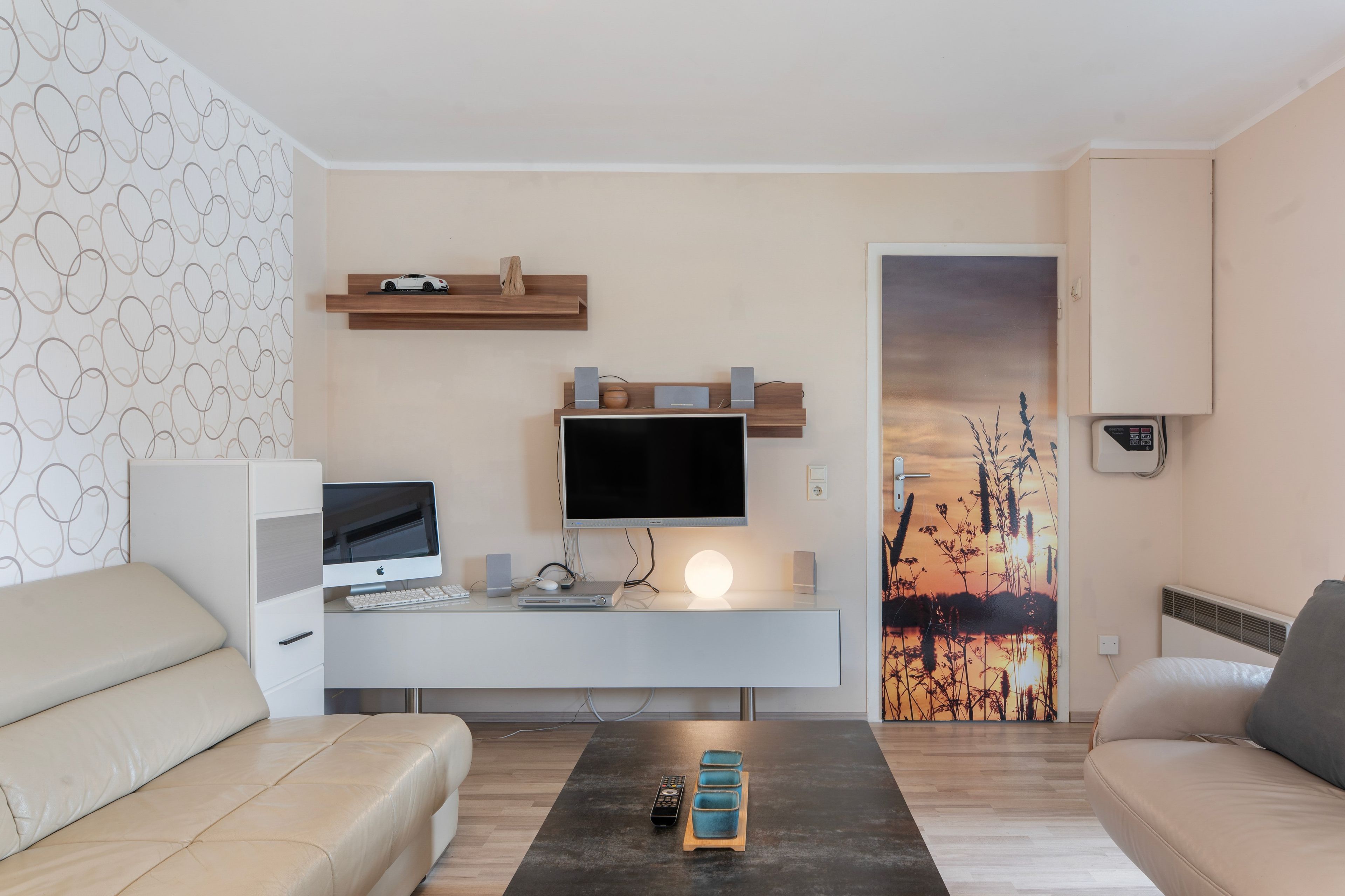 A modern living room with a flat-screen TV, a desk with a computer, and a sofa.