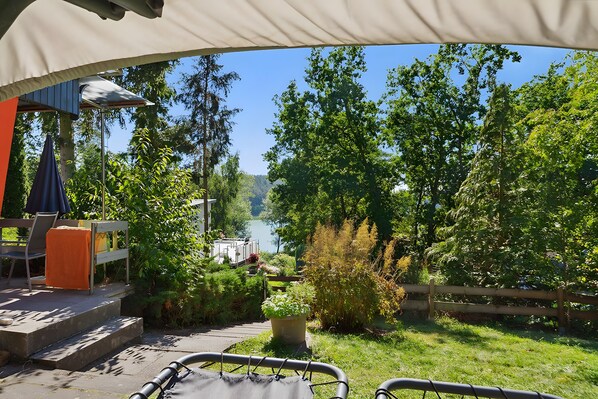 A covered outdoor seating area with a view of a lake and surrounding greenery.