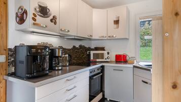 A compact kitchen with white cabinets, a coffee machine, a microwave, and a toaster.