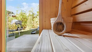 Banco de sauna de madera con un cucharón de madera y un recipiente blanco.