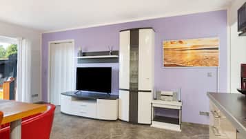 Ein modernes Wohnzimmer mit Fernseher, einer Glasvitrine und einem Gemälde an der Wand.