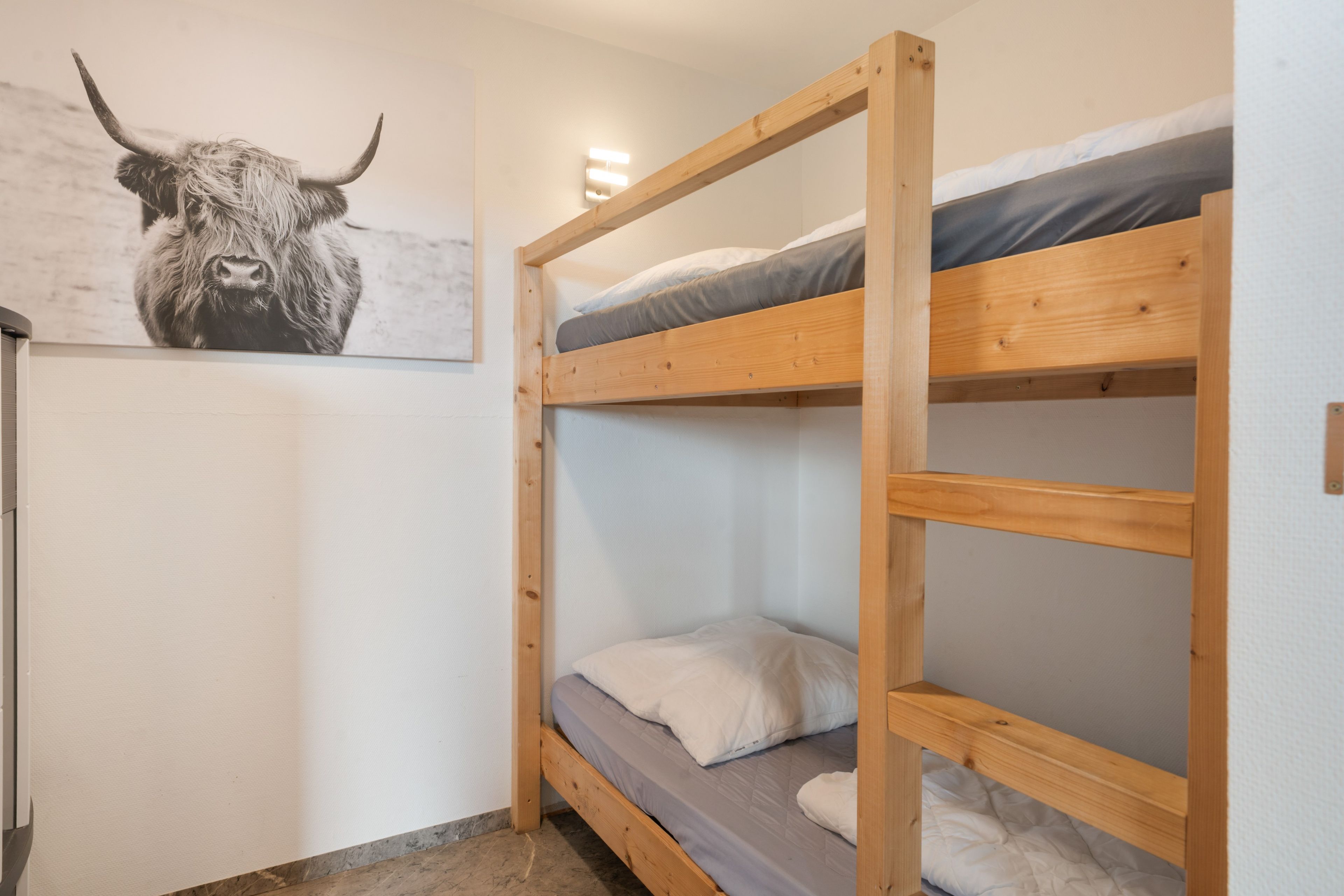 Ein Schlafraum mit Etagenbetten und einem Bullenbild an der Wand.