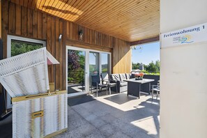 A covered outdoor seating area with a wooden ceiling, a glass door leading outside, and a sign indicating 'Ferienwohnung 1'. - Apartment “Zum Segel” 1 with Private Terrace and Wi-Fi (Zadelsdorf)